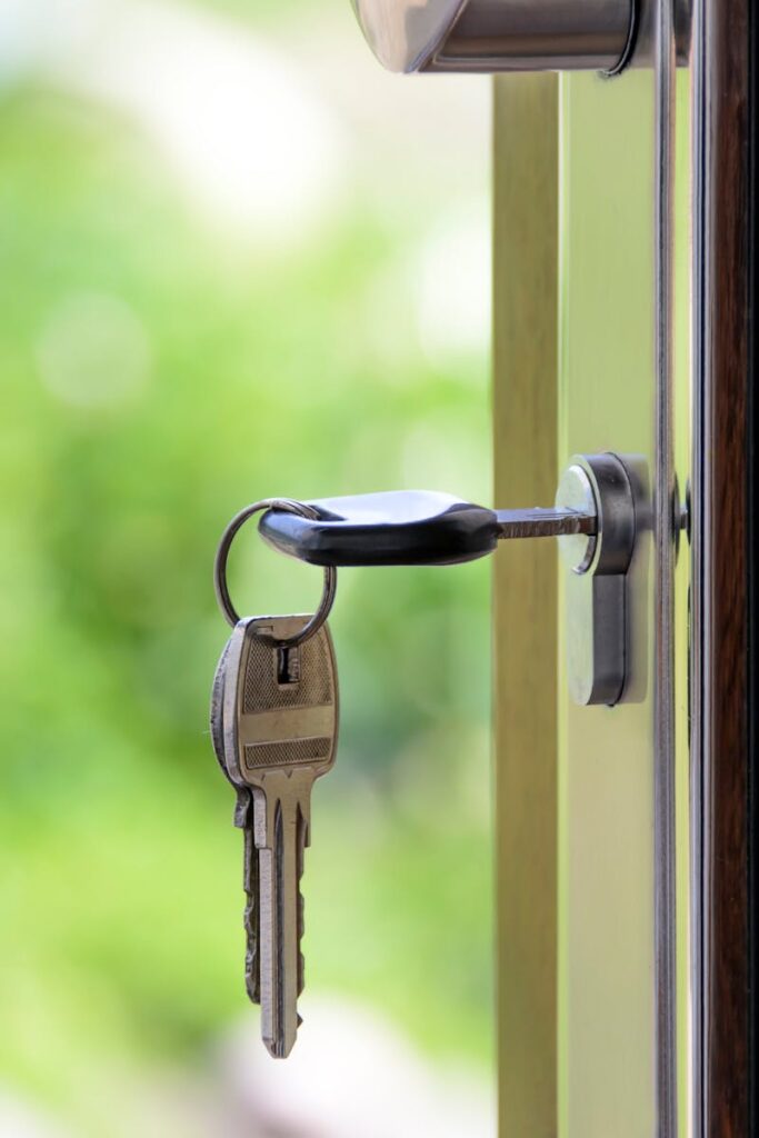 Key inserted in door lock against a blurred green background, symbolizing security and real estate.